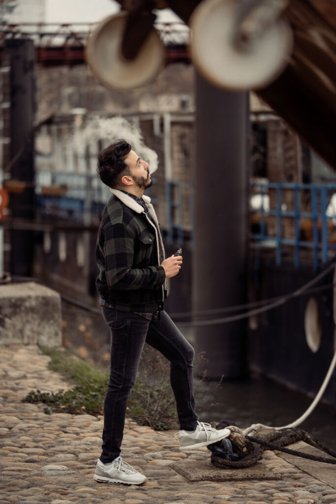 Photographie lifestyle d’un jeune homme qui fume devant des péniches lyonnaises